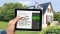 Tablette avec calculateur de modernisation ; à l'arrière-plan : maisons individuelles
